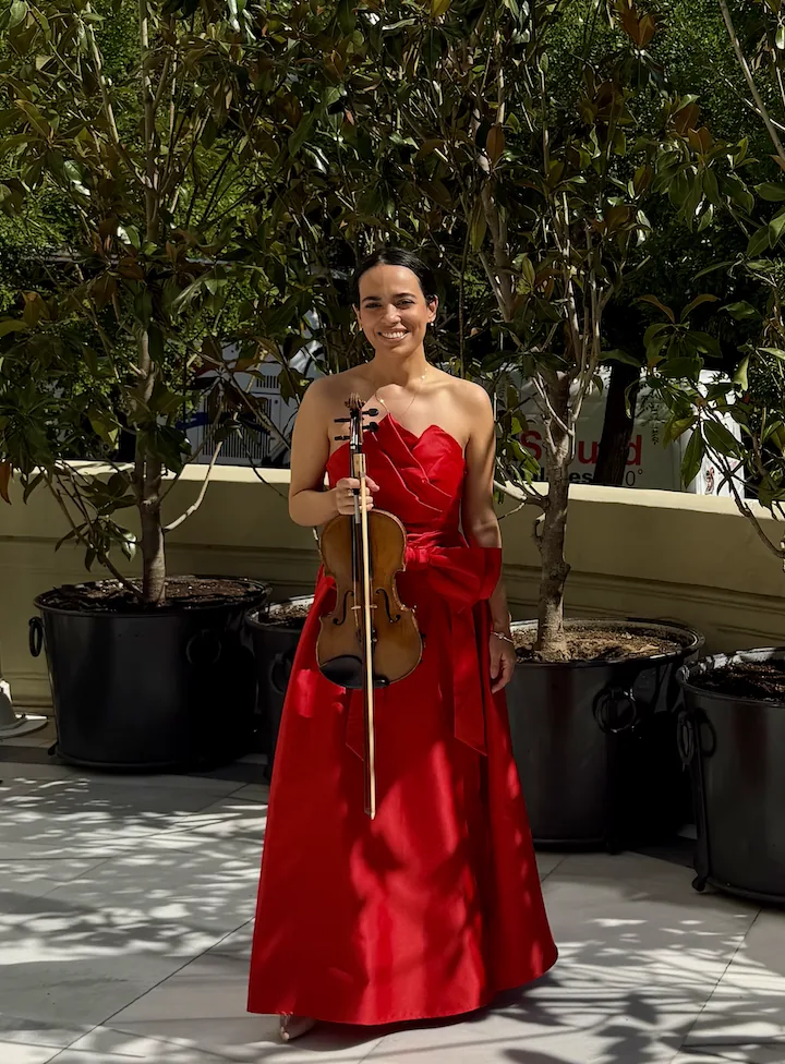 Lia Violinista con vestido rojo y su violín en una terraza de Madrid
